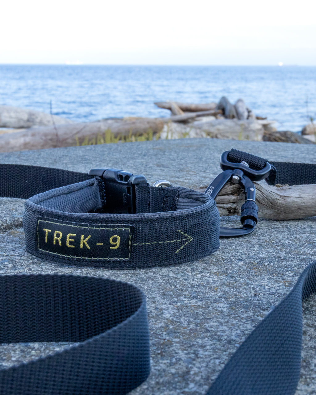 A black Trek-9 Dog leash with aluminum swivel carabiner, nickel plated d ring, air mesh padded handle, and rugged side release buckle, made from high quality nylon webbing
